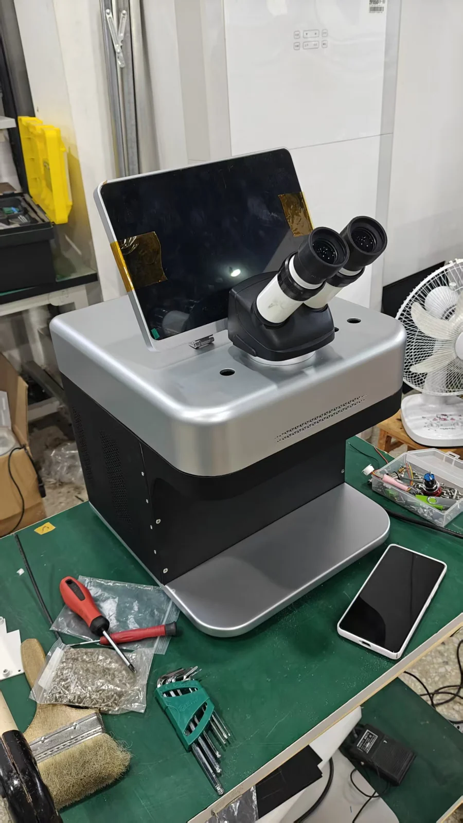 The M3 on a working bench beside a phone, the footprint row of these jewelry laser welder specifications shown against a real object